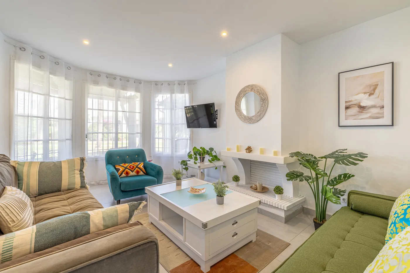 El mismo salón después: color en capas, un sillón turquesa, plantas y cuadros.